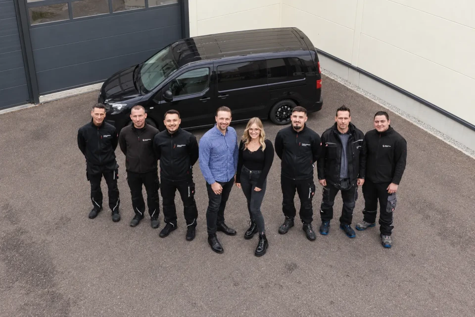 Das GDK-Team vor einem Fahrzeug am Betriebsgebäude
